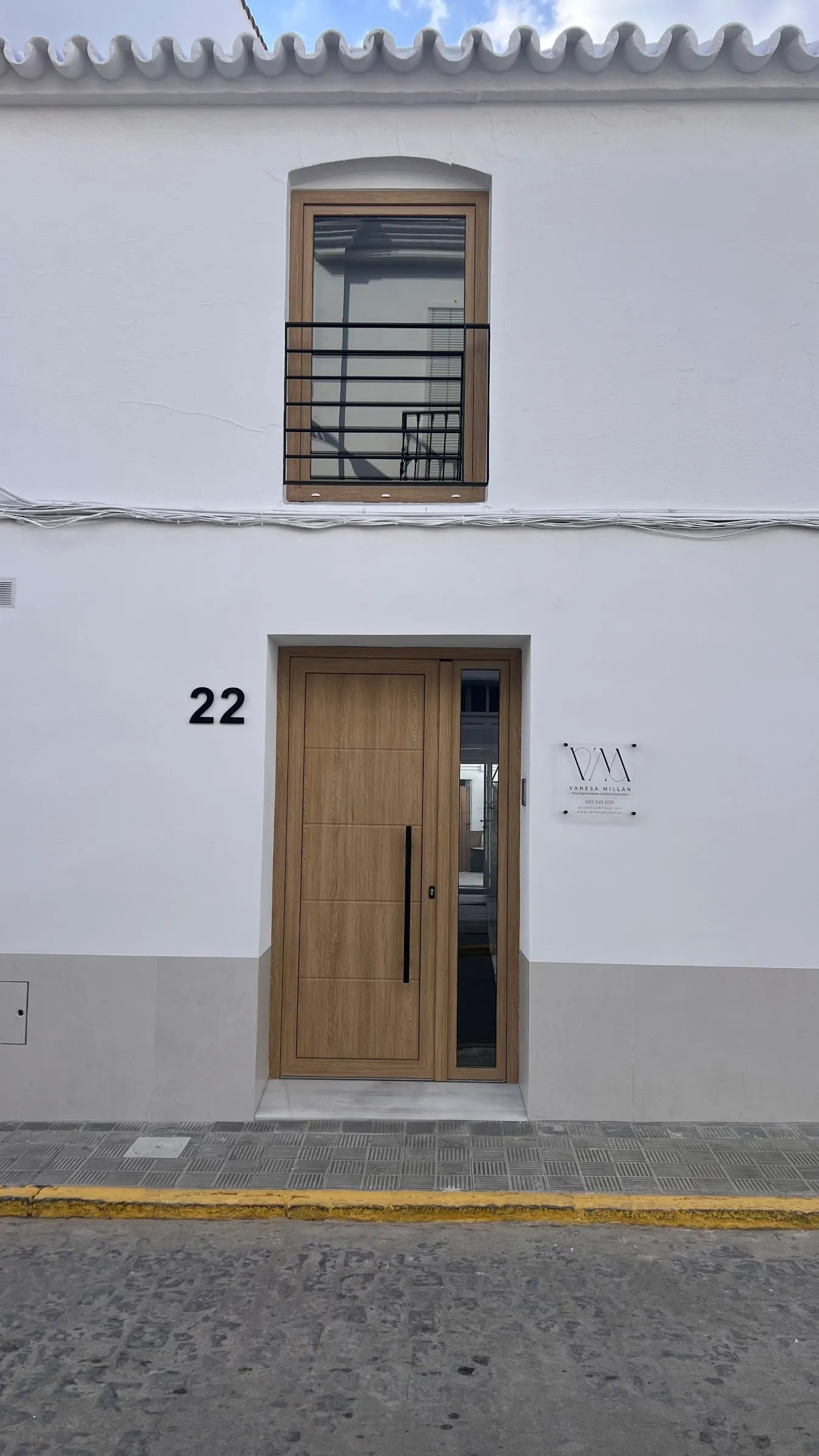 Fachada blanca del centro, con su puerta de madera y el número 22